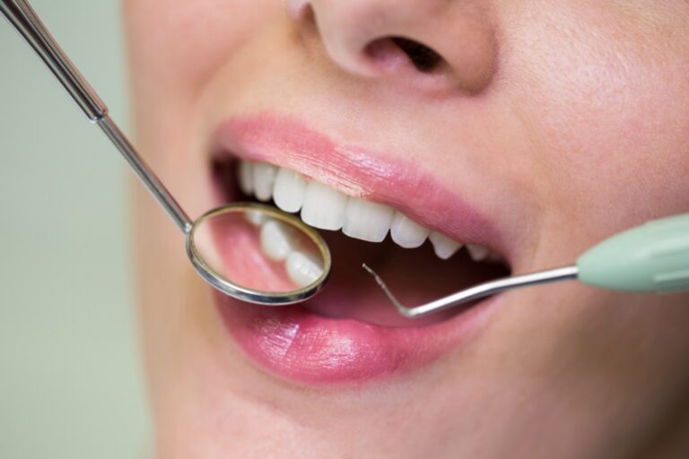 Dentist examining a female patient with tools